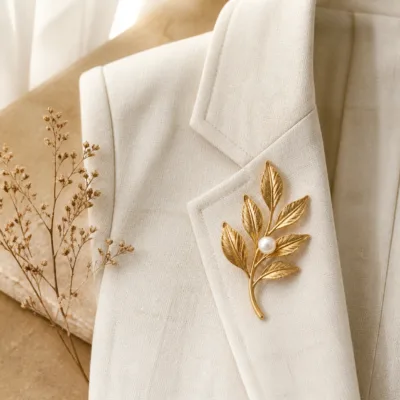 Alfinete ramo de folhas dourado com pérola sobre blazer de linho