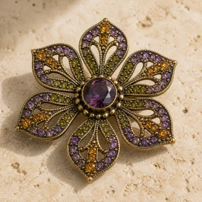 Alfinete flor dourado com cristais roxos e verdes em detalhe