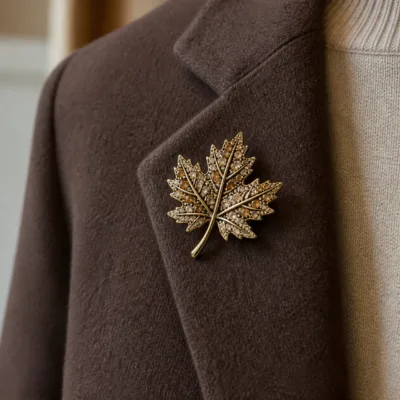 Alfinete folha de ácer dourado aplicado num blazer castanho