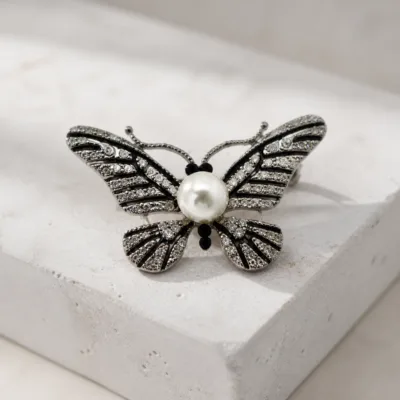 Alfinete borboleta prateado com cristais e pérola