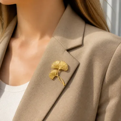 Alfinete dourado com folhas de ginkgo numa lapela