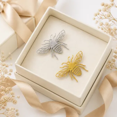 Alfinetes de abelha prateado e dourado numa caixa de joalharia