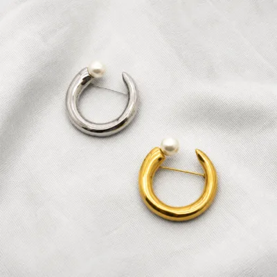 Alfinetes circulares dourado e prateado com pérola sobre linho