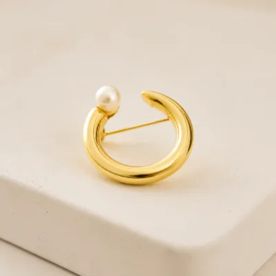 Alfinete circular dourado com pérola em pormenor