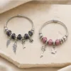 Duas pulseiras de charms com pena e chave nos modelos preto e rosa