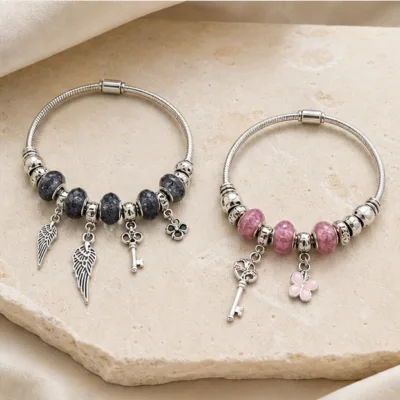 Duas pulseiras de charms com pena e chave nos modelos preto e rosa