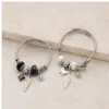 Duas pulseiras de charms com pena e chave nos modelos preto e roxo e branco pérola