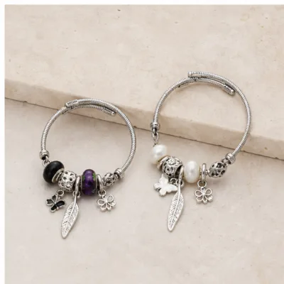 Duas pulseiras de charms com pena e chave nos modelos preto e roxo e branco pérola