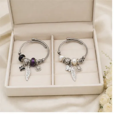 Pulseiras de charms preta e roxa e branca numa caixa de joalharia