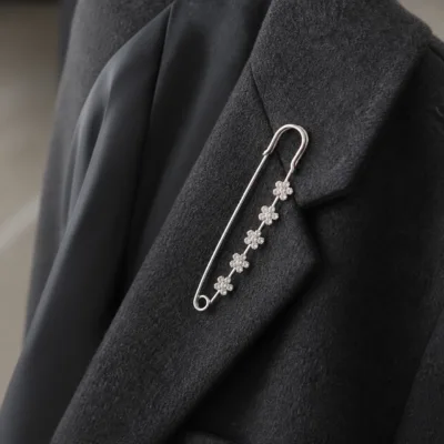 Alfinete de segurança prateado com cristais florais aplicado num blazer cinzento