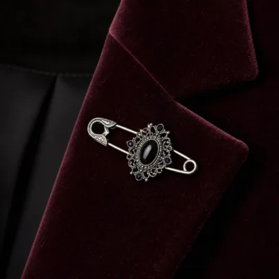 Alfinete vintage prateado aplicado num blazer de veludo bordô