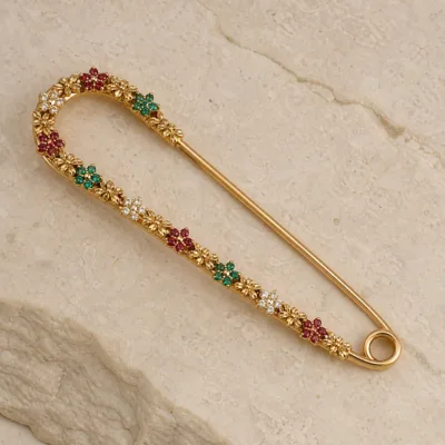 Alfinete dourado com cristais vermelhos verdes e transparentes