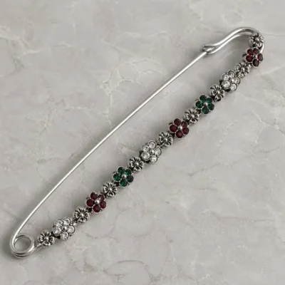 Alfinete prateado com cristais vermelhos verdes e transparentes