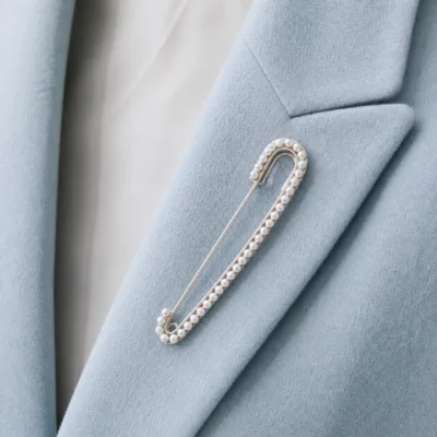 Alfinete prateado com pérolas aplicado num blazer azul-claro