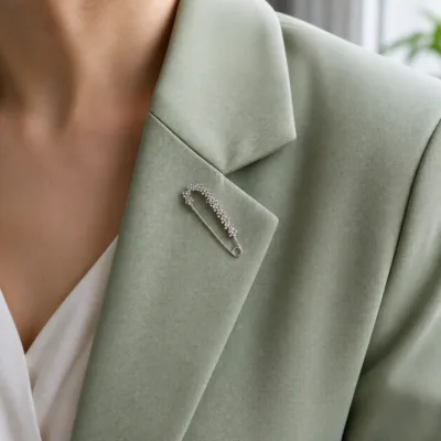 Alfinete floral prateado aplicado num blazer verde-sálvia