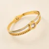Bracelete dourado com corrente e cristal redondo central