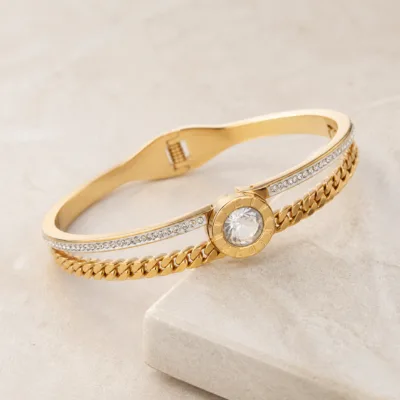 Bracelete dourado com cristais sobre pedra clara
