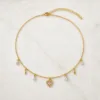 Colar dourado delicado com pendente e cristais sobre fundo claro