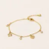 Pulseira dourada com motivos prateados e cristais sobre fundo claro