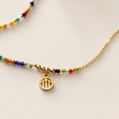Pormenor das missangas multicolores e do pendente dourado