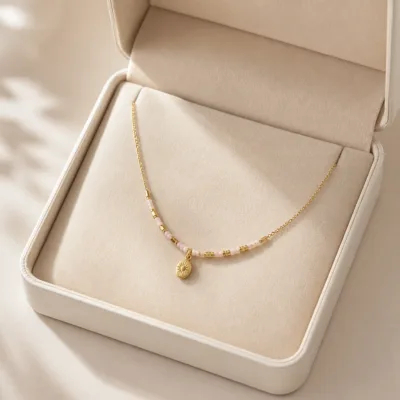 Colar dourado com missangas rosa-claro em caixa de joalharia