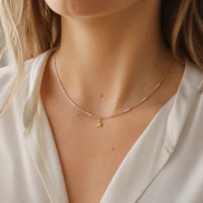 Colar dourado com missangas rosa-claro usado ao pescoço