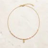 Colar dourado com missangas rosa-claro sobre fundo claro