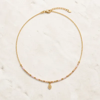 Colar dourado com missangas rosa-claro sobre fundo claro