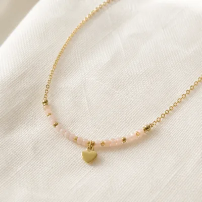 Pormenor das missangas rosa-claro e do pendente dourado