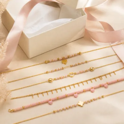 Colar dourado com missangas rosa-claro em caixa de joalharia