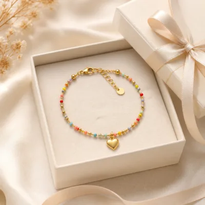 Pulseira dourada com missangas multicolores e pendente em caixa de joalharia