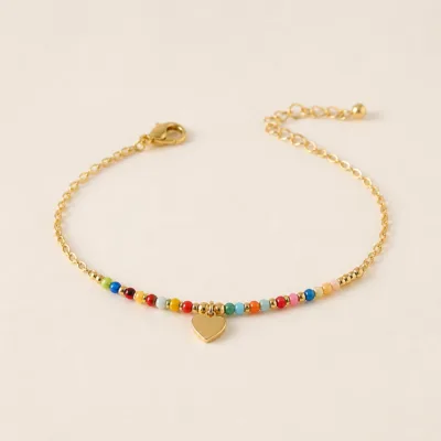 Pulseira dourada com missangas multicolores e pendente sobre fundo claro