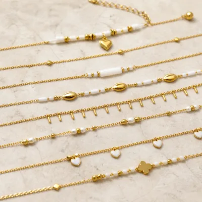 Pormenor das missangas brancas, pérola e pendente e do pendente dourado