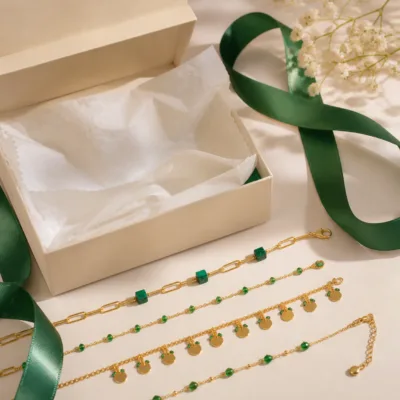 Colar dourado com missangas verdes em caixa de joalharia
