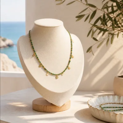 Colar dourado com missangas verdes usado ao pescoço