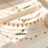 Colar dourado com missangas verdes sobre fundo claro