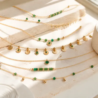 Colar dourado com missangas verdes sobre fundo claro