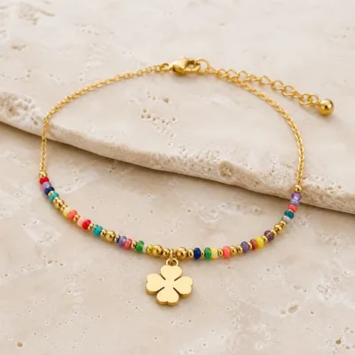 Pormenor das missangas multicolores, elos ovais e pendente de trevo e do pendente dourado
