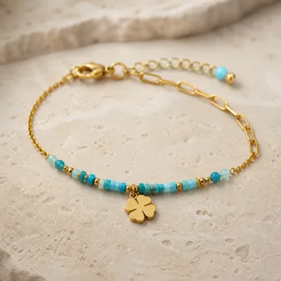 Pormenor das missangas azul-claro e turquesa, elos ovais e pendente de trevo e do pendente dourado