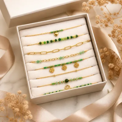 Pulseira dourada com missangas verdes, elos ovais e pendente de trevo em caixa de joalharia