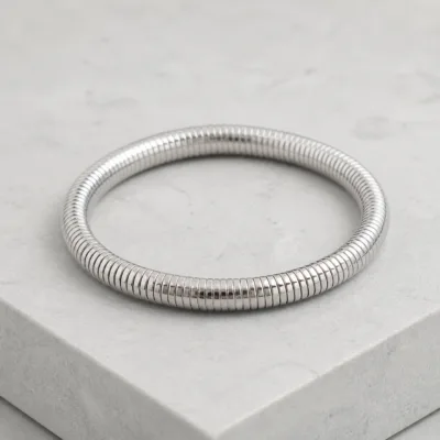 Pulseira prateada canelada sobre pedra clara