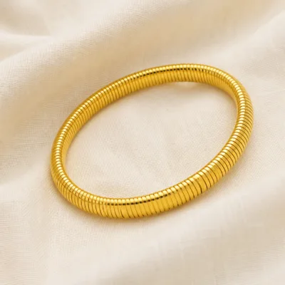 Pulseira flexível dourada sobre linho claro