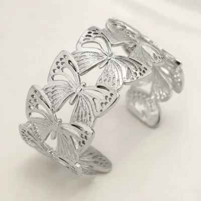 Detalhe das asas vazadas do bracelete prateado com borboletas