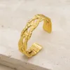 Bracelete Modelo A dourado aberto com três faixas trançadas e textura