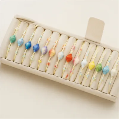 Conjunto de 24 pulseiras com conchas coloridas num expositor de joalharia