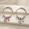 Duas pulseiras de charms florais em aço nos modelos rosa e branco