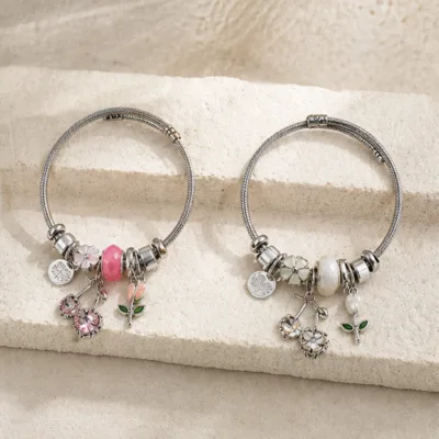 Duas pulseiras de charms florais em aço nos modelos rosa e branco