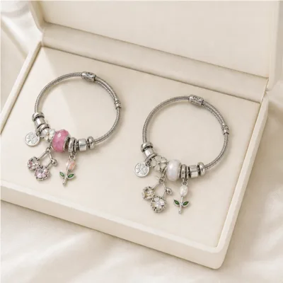 Pulseiras de charms florais rosa e branca numa caixa de joalharia
