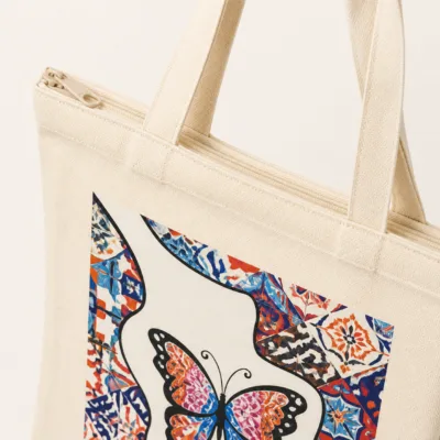 Detalhe da lona, das costuras e do fecho da mala tote com borboleta