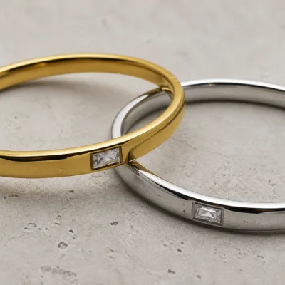 Pormenor das zircónias quadradas nas pulseiras dourada e prateada
